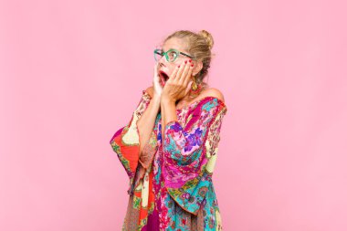 Orta yaşlı bir kadın, mutlu, heyecanlı ve şaşırmış hissediyor, iki eli yüzü yana bakıyor.