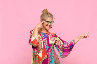 Orta yaşlı bir kadın gülüyor, mutlu, pozitif ve şaşırmış görünüyor, yanal fotokopi alanını işaret eden harika bir fikrin farkına varıyor.