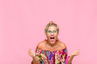 Orta yaşlı kadın son derece mutlu ve şaşırmış görünüyor, başarıyı kutluyor, bağırıyor ve zıplıyor.