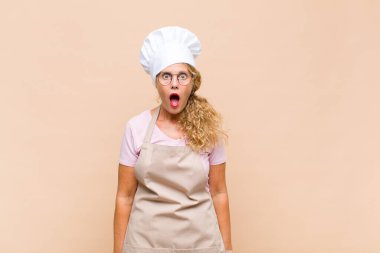 Orta yaşlı fırıncı kadın şok olmuş ya da şaşırmış görünüyor, ağzı açık bir şekilde 