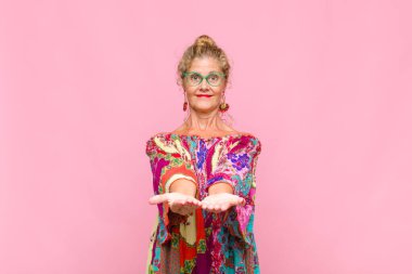 Orta yaşlı kadın mutlu bir şekilde gülümsüyor arkadaş canlısı, kendinden emin, olumlu bakışlı, bir nesne ya da konsept sunuyor ve gösteriyor.