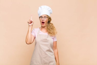 Orta yaşlı fırıncı neşeli ve mutlu bir şekilde gülümsüyor, tek eliyle boşluğu dolduruyor.