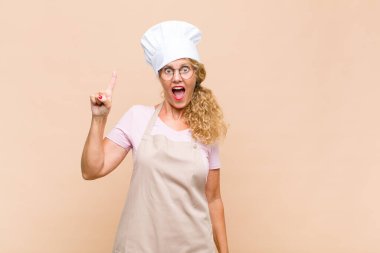 Orta yaşlı fırıncı bir fikri fark ettikten sonra kendini mutlu ve heyecanlı bir dahi gibi hisseder, neşeli bir şekilde parmağını kaldırır, eureka!