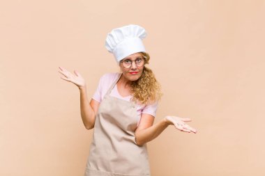 Orta yaşlı fırıncı şaşkın, şaşkın ve stresli görünüyor, farklı seçenekler arasında merak ediyor, kararsız hissediyor