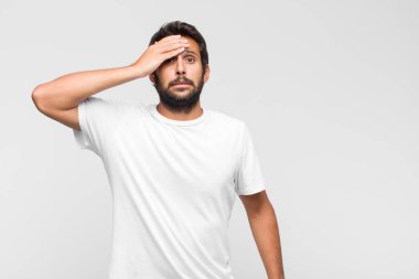 Genç Latin yakışıklı adam mutlu, gururlu ve şaşırmış görünüyor, neşeli bir şekilde kendini gösteriyor, kendinden emin ve yüce hissediyor.