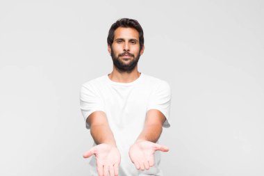 Genç Latin yakışıklı adam mutlu bir şekilde gülümsüyor, arkadaş canlısı, kendinden emin, olumlu bakışlı, bir nesne ya da konsept sunuyor ve gösteriyor.