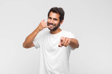 Genç Latin yakışıklı adam neşeyle gülümsüyor ve kamerayı işaret ediyor. Sonra seni arıyor, telefonla konuşuyor.