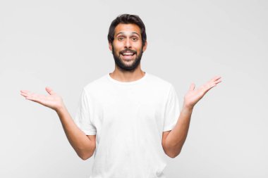 Genç Latin yakışıklı adam mutlu, heyecanlı, şaşırmış ya da şok olmuş, gülümseyen ve hayrete düşmüş hissediyor.