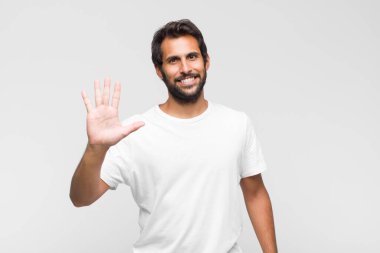 Genç Latin yakışıklı adam gülümsüyor ve arkadaş canlısı görünüyor, 5 ya da 5 numarayı gösteriyor, eli önde, geri sayıyor.