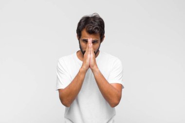 Genç Latin yakışıklı adam endişeli, umutlu ve dindar, avuçlarına bastırılmış, af dileyen, sadakatle dua eden