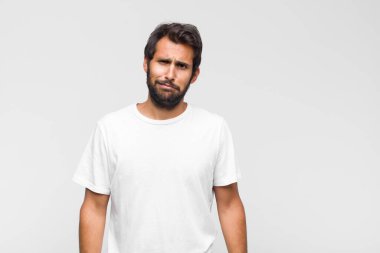 Genç Latin yakışıklı adam gülüyor, mutlu, pozitif ve şaşırmış görünüyor, yanal fotokopi alanını işaret eden harika bir fikri fark ediyor.