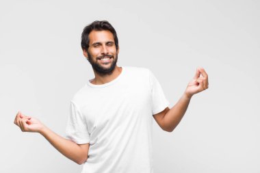 Genç Latin yakışıklı adam gülümsüyor, kaygısız hissediyor, rahat ve mutlu, dans ediyor ve müzik dinliyor, bir partide eğleniyor.