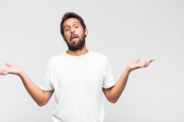 Genç Latin yakışıklı adam panik ya da öfke içinde bağırıyor, şok olmuş, korkmuş ya da öfkeli, elleri başının yanında.