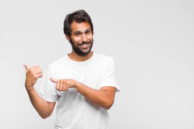 Genç Latin yakışıklı adam şok olmuş, mutlu, şaşkın ve şaşırmış hissediyor, ağzı açık bir şekilde yana bakıyor.