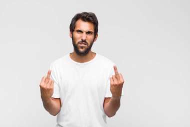 Genç Latin yakışıklı bir adam stresli ve hayal kırıklığına uğramış hissediyor, ellerinizi havaya kaldırıyor, yorgun, mutsuz ve migren ağrısı çekiyor.