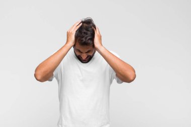 Genç Latin yakışıklı adam stresli, hayal kırıklığına uğramış ve yorgun, endişeli ve sorunlu bir bakışla boynunu ovalıyor.