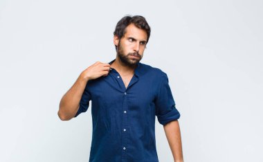 Genç Latin yakışıklı adam stresli, yorgun ve hayal kırıklığına uğramış görünüyor, alnından ter damlıyor, umutsuz ve bitkin hissediyor.