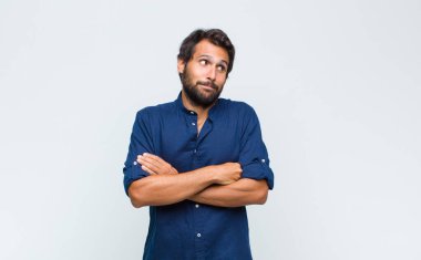 Genç Latin yakışıklı adam ciddi, düşünceli ve endişeli, elleri çenesine bastırılmış şekilde yan bakıyor.