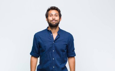 Genç Latin yakışıklı adam pozitif ve kendinden emin gülümsüyor. Tatmin olmuş, arkadaş canlısı ve mutlu görünüyor.