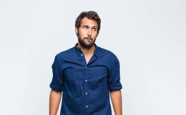 Şaşkın ve kafası karışık görünen genç Latin bir adam bir sorunu çözmeye çalışıyor ya da düşünüyor.