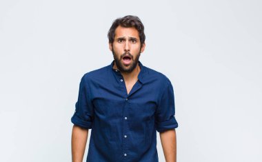 Şok olmuş, kızgın, sinirli ya da hayal kırıklığına uğramış, ağzı açık ve öfkeli görünen genç Latin bir adam.