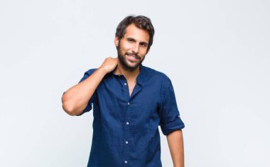 Genç Latin yakışıklı adam neşeli ve kendinden emin bir şekilde gülüyor, mutlu, samimi bir gülümsemeyle.