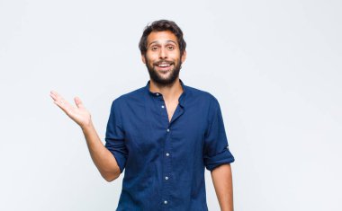 Genç Latin yakışıklı adam kendini mutlu, şaşırmış ve neşeli hissediyor. Pozitif bir tavırla gülümsüyor. Bir çözüm ya da fikri fark ediyor.