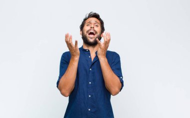 Genç Latin yakışıklı adam umutsuz ve hayal kırıklığına uğramış görünüyor, stresli, mutsuz ve sinirli, bağırıyor ve çığlık atıyor.