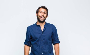 Genç Latin yakışıklı adam mutlu ve hoş bir şekilde şaşırmış görünüyor. Büyülenmiş ve şok olmuş bir ifadeyle heyecanlanıyor.