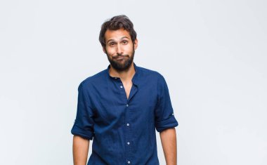 Genç Latin yakışıklı adam kafası karışık ve şüpheli hissediyor, merak ediyor ya da karar vermeye çalışıyor.