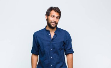 Genç Latin yakışıklı adam şok olmuş, mutlu, şaşkın ve şaşırmış hissediyor, ağzı açık bir şekilde yana bakıyor.