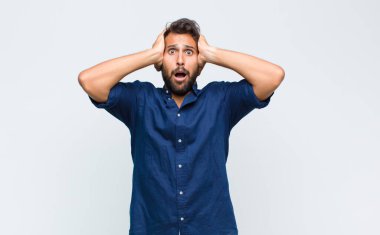 Genç Latin yakışıklı adam dehşete kapılmış ve şok olmuş hissediyor, ellerini havaya kaldırıyor ve bir hata yüzünden panikliyor.