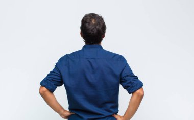 Genç Latin yakışıklı adam kafası karışık ya da dolu ya da şüphe ve soru dolu, merak ediyor, elleri kalçasında, dikiz aynasından