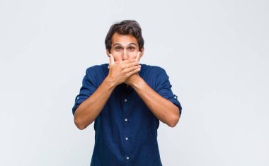 Şok olmuş, şaşırmış bir ifadeyle ağzı kapalı genç Latin yakışıklı bir adam sır saklıyor ya da 