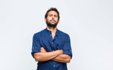 Genç Latin yakışıklı adam hayal kırıklığına uğramış ve hayal kırıklığına uğramış, ciddi görünüyor, kızgın ve kollarını kavuşturmuş.