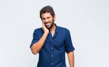 Genç, yakışıklı, yanak tutan ve acı çeken diş ağrısı çeken, hasta, sefil ve mutsuz, dişçi arayan Latin bir adam.