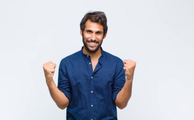 Genç Latin yakışıklı adam mutlu, pozitif ve başarılı hissediyor, zaferi, başarıları veya iyi şansı kutluyor.