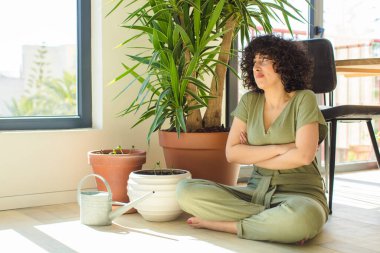 Genç, güzel bir Arap kadın evinde, elinde bir su bidonu ve bitkilerle.