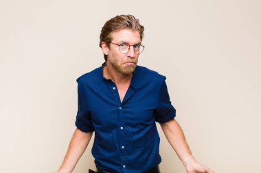 blonde adult caucasic man feeling clueless and confused, having no idea, absolutely puzzled with a dumb or foolish look
