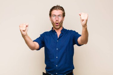 Sarışın, yetişkin, beyaz bir adam inanılmaz bir başarıyı kutluyor. Kazanan gibi, heyecanlı ve mutlu görünüyor.!