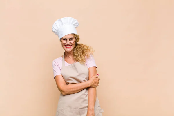 middle age woman baker laughing shyly and cheerfully, with a friendly and positive but insecure attitude