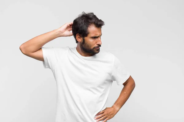 Jovem Latino Bonito Homem Sentindo Perplexo Confuso Coçando Cabeça Olhando — Fotografia de Stock