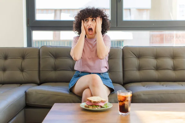 Joven Bonita Árabe Mujer Teniendo Sándwich Sentado Sofá Casa —  Fotos de Stock