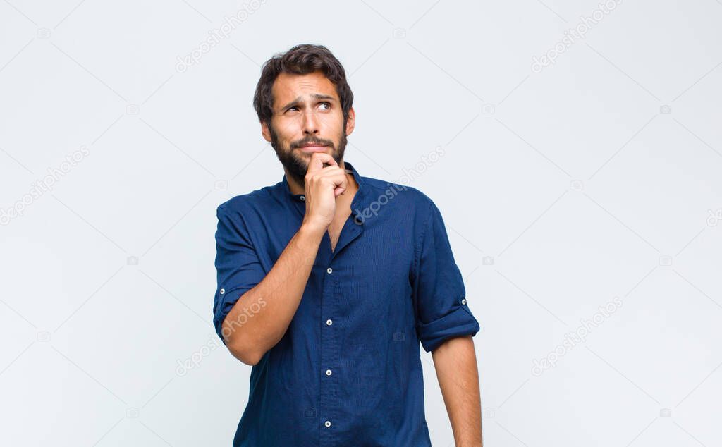 young latin handsome man thinking, feeling doubtful and confused, with different options, wondering which decision to make