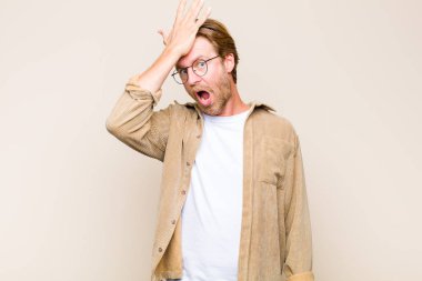 blonde adult caucasic man raising palm to forehead thinking oops, after making a stupid mistake or remembering, feeling dumb