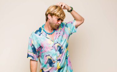 Kafası karışmış, kafası karışmış, kaşınan ve yan tarafa bakan sarışın, beyaz bir adam.