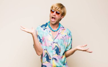 Kafası karışmış, kafası karışmış ve stresli görünen sarışın yetişkin bir adam farklı seçenekler arasında merak ediyor, kararsız hissediyor.