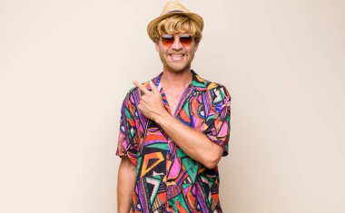 Sarışın, yetişkin gezgin, neşeli bir şekilde gülümseyen, mutlu hisseden, kenarı ve yukarıyı gösteren, kopya uzayda nesne gösteren