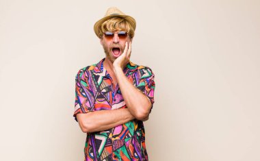 Sarışın, yetişkin bir gezgin şok ve inançsızlıkla ağzı açık, elleri yanağında ve kolları çaprazlanmış, sersemlemiş ve şaşkın hissediyordu.