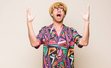 Sarışın, yetişkin, mutlu, şaşkın, şanslı ve şaşırmış hisseden gezgin, zaferi iki eli havada kutluyor.